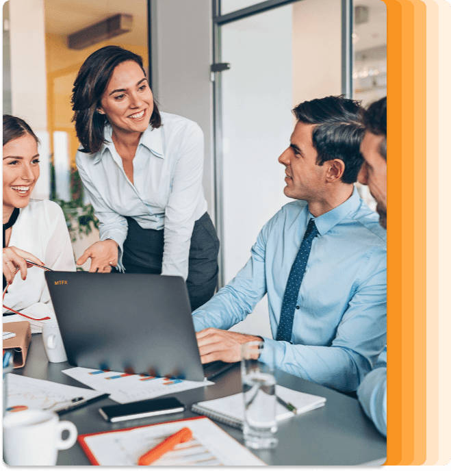 Smiling team of professionals having a discussion around a laptop in a modern office