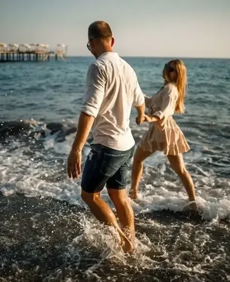 Couple walking along the beach shore, enjoying the waves and holding hands