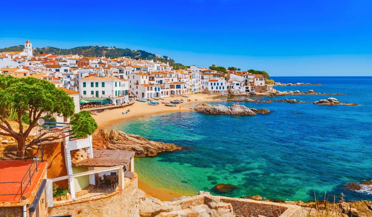 Scenic Mediterranean coastal town with colorful buildings and clear turquoise waters, representing property investment or travel transfers in southern Europe