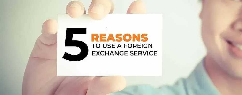 Close-up of a person holding a card that reads “5 Reasons to Use a Foreign Exchange Service,” highlighting key benefits of FX services.