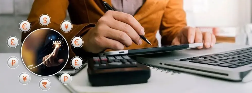 Person using calculator and tablet beside a laptop, with global currency symbols representing exchange rate optimization and saving on currency conversion fees.