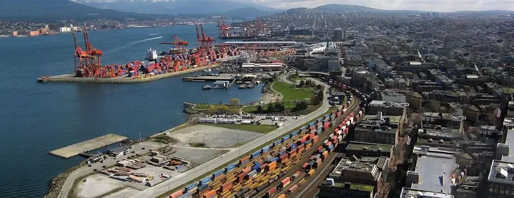 Aerial view of a busy port with container ships, cranes, and colorful freight trains, symbolizing international trade and cross-border supplier payments.