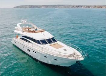 Luxury white yacht cruising on calm blue water with coastline in the background