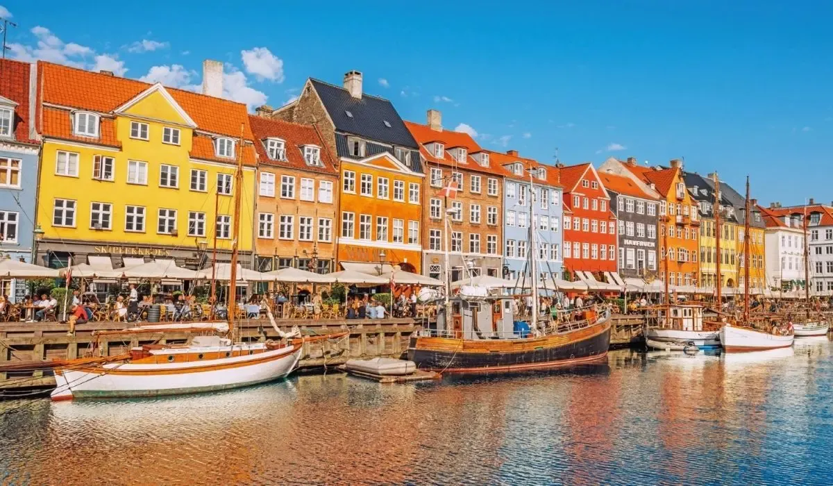 Scenic view of colorful buildings, boats, and waterfront cafes at Nyhavn harbor in Copenhagen, Denmark.