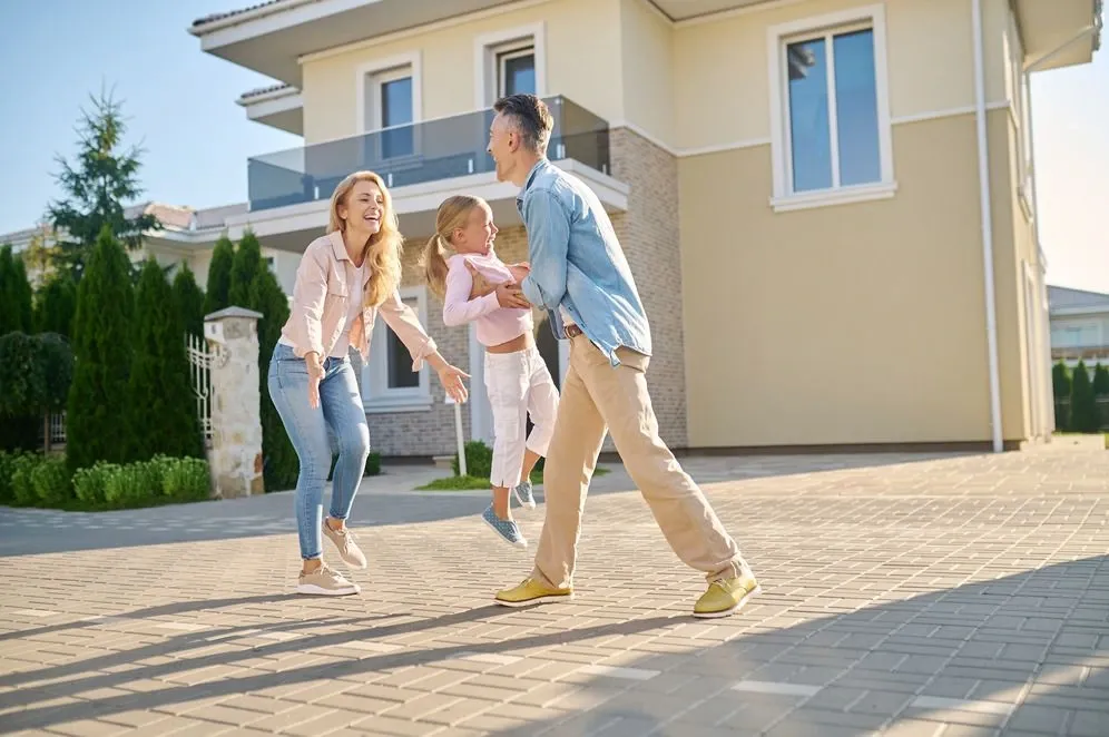 Happy family playing together outside their new home on a sunny day, symbolizing inheritance or property transfer.