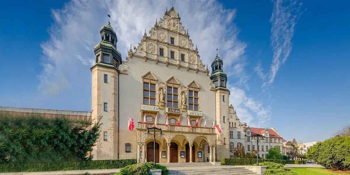 Historic cream colored university building with towers and Polish flags in Poznań. MTFX offers Canadian students a secure way to pay tuition to Poland in PLN while saving on fees and currency exchange.