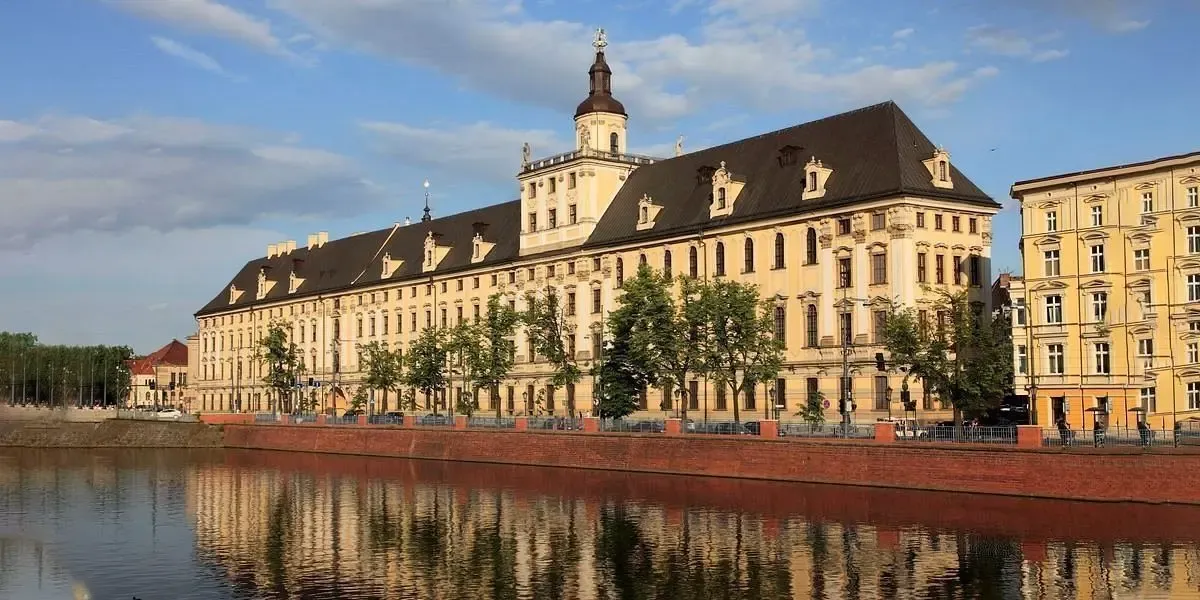 Elegant baroque main building of the University of Wrocław along the Odra River at sunset. Canadian students can make affordable tuition transfers to Poland from Canada with MTFX and avoid hidden banking fees.