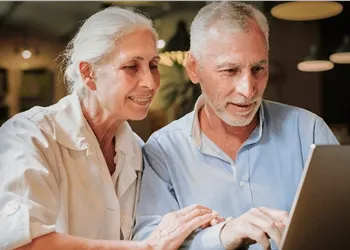 Smiling elderly couple looking at a laptop together at home