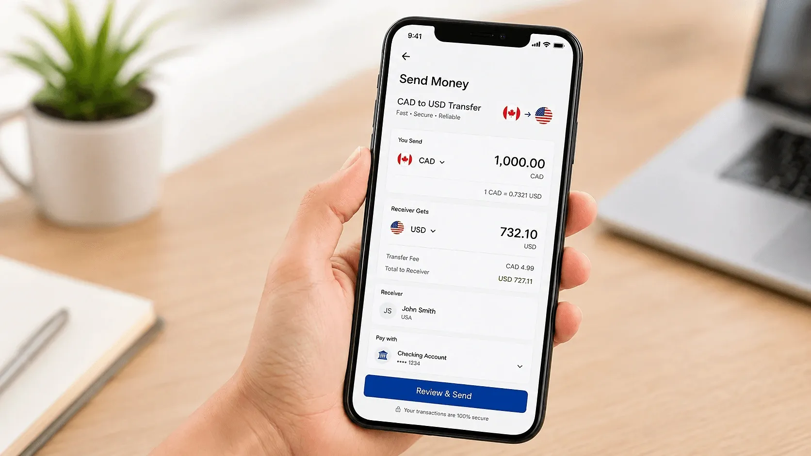 Hand holding a smartphone displaying a CAD to USD international money transfer with exchange rate and payment details.