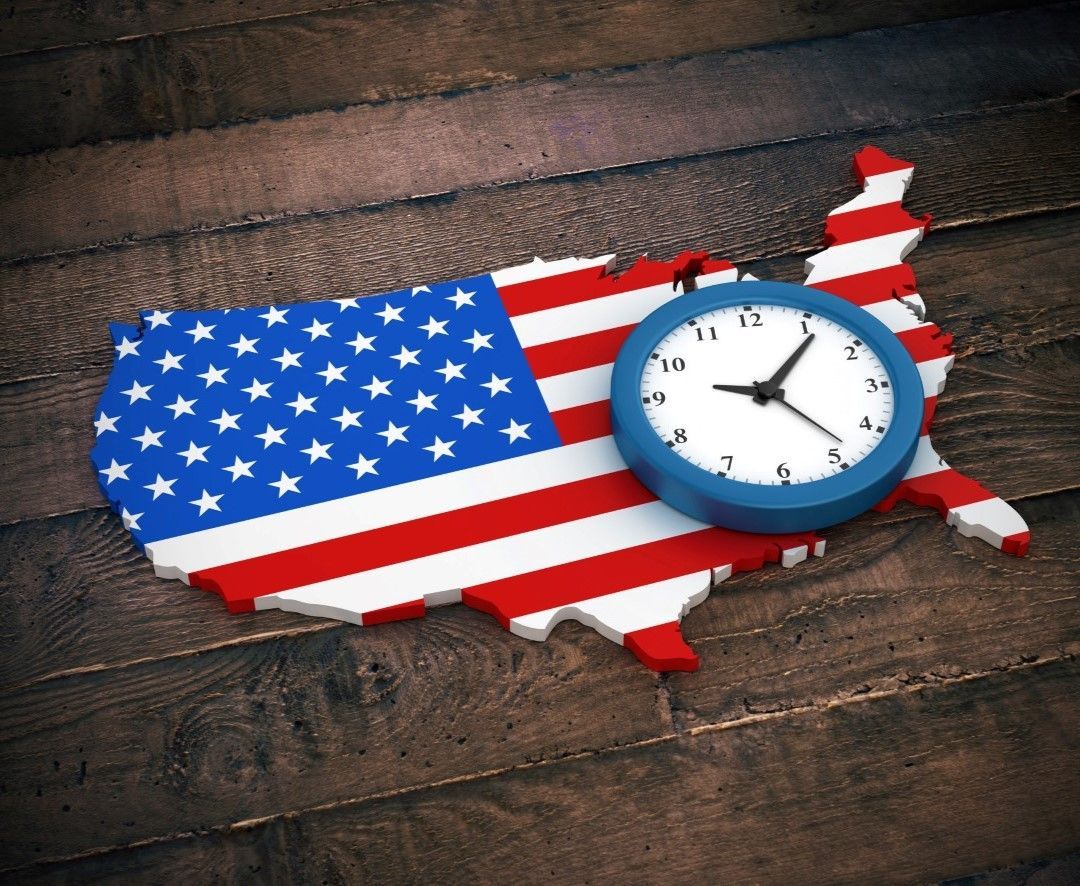 A 3D illustration of the United States map covered in the American flag with a blue-rimmed clock placed over it, symbolizing time it takes for the payment to reach US.