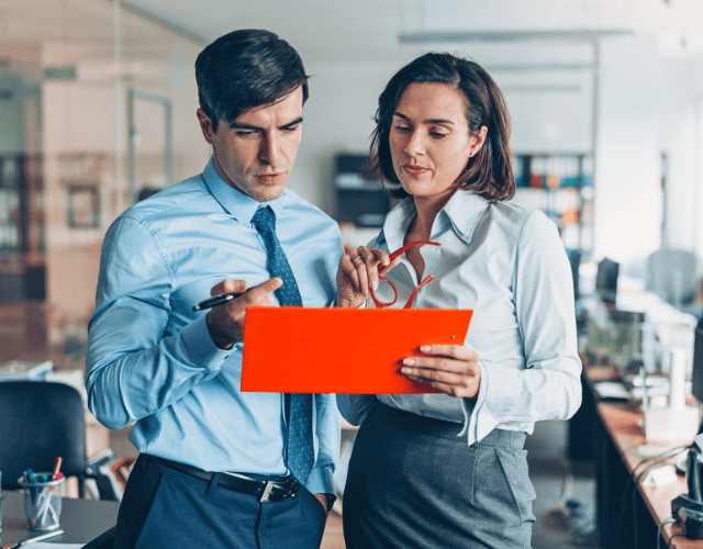 Two business professionals discussing documents in a modern office setting