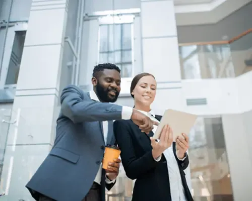 Two business professionals reviewing content on a tablet in a modern office building